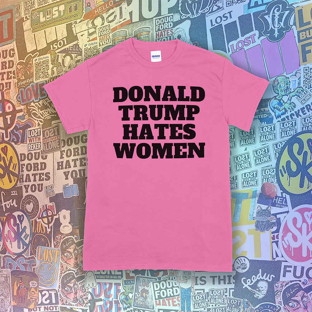 Donald Trump Hates Women t-shirt. Bold letters screen printed with black ink on an azalea pink shirt. A huge amount of graffiti stickers in the background.
