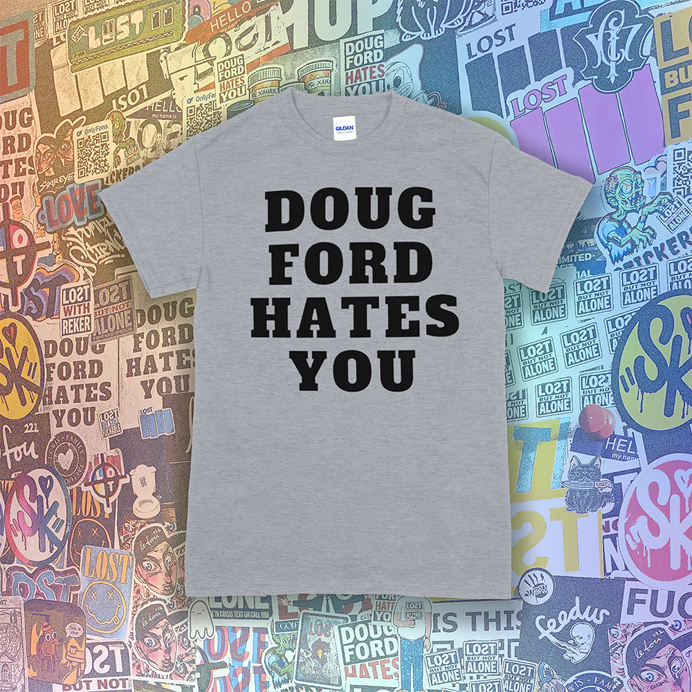 The original Doug Ford Hates You t-shirt. Bold black letters screen printed on a grey shirt. Assorted colorful graffiti stickers make up the background.