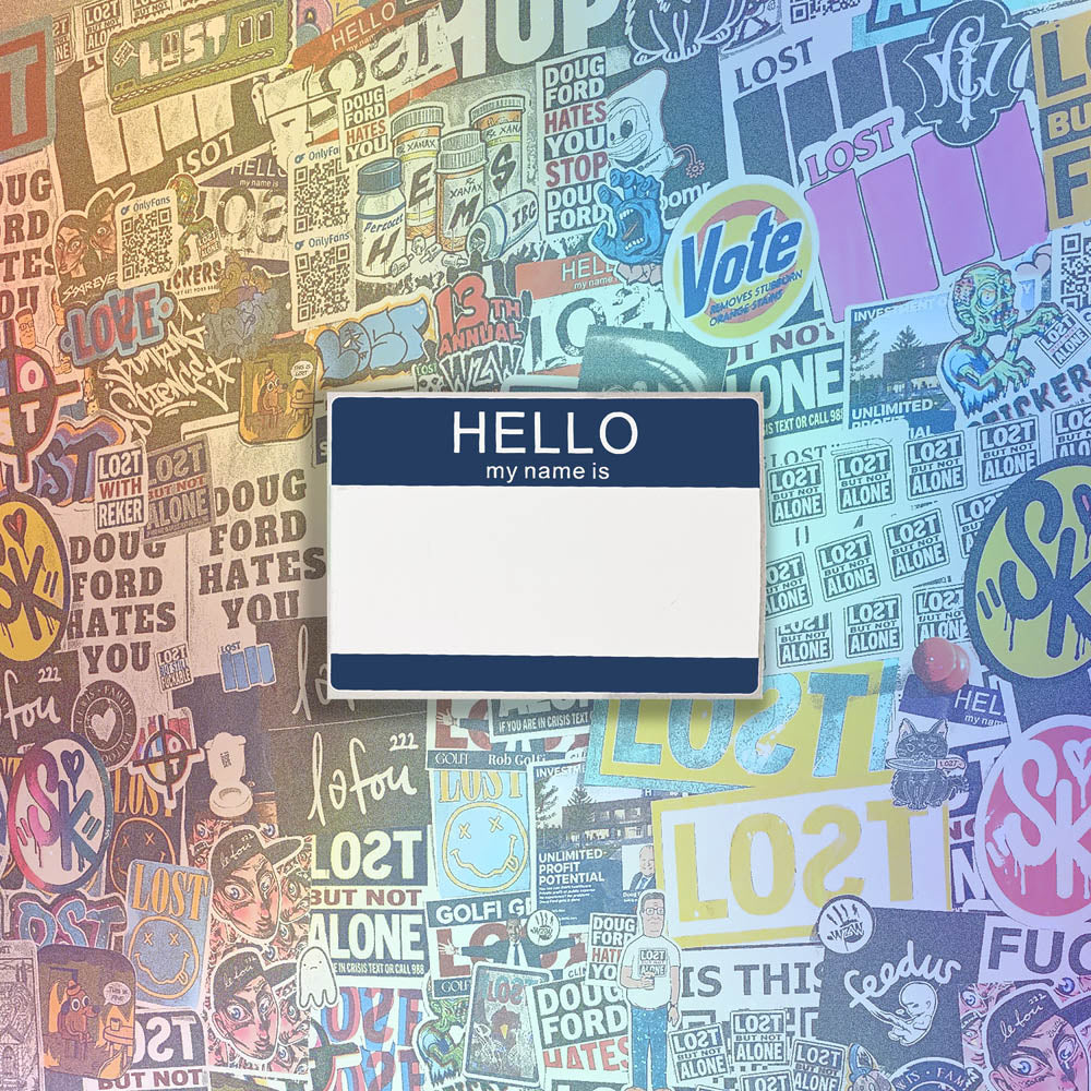 Hello my name is blank nametag sticker. A blue and white nametag sticker waiting to be tagged. The sticker is set against a wall of colorful graffiti stickers.