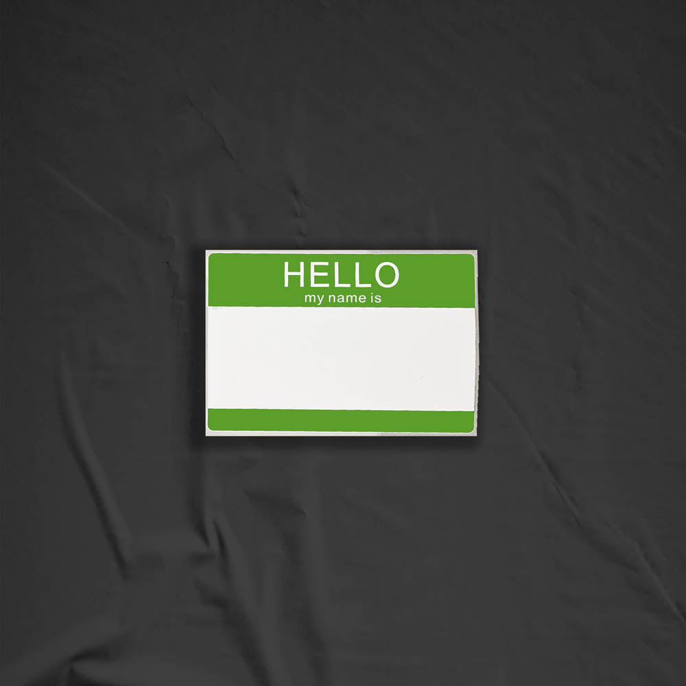 Hello my name is blank nametag sticker. A green and white nametag sticker waiting to be tagged. The sticker is set against a black background.