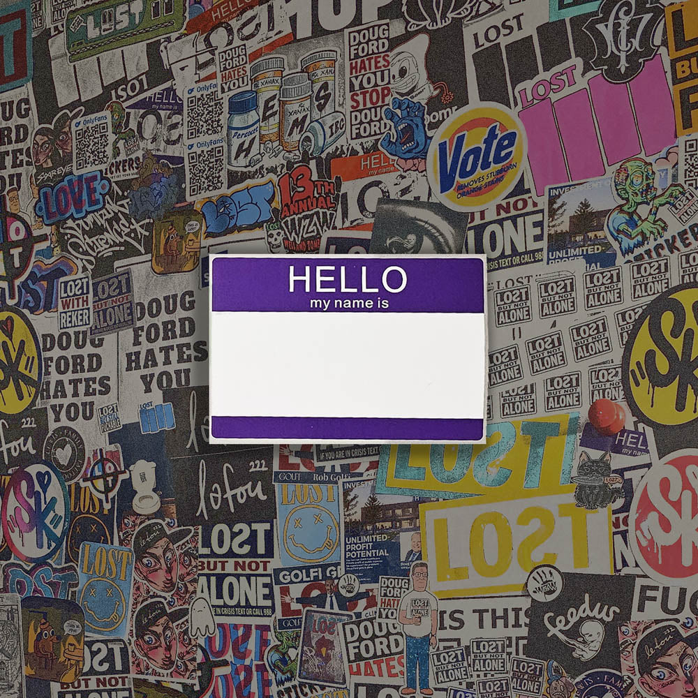 Hello my name is blank nametag sticker. A purple and white nametag sticker waiting to be tagged. The sticker is set against a wall of colorful graffiti stickers.