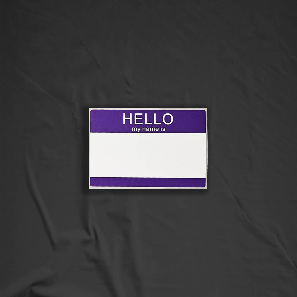 Hello my name is blank nametag sticker. A purple and white nametag sticker waiting to be tagged. The sticker is set against a black background.