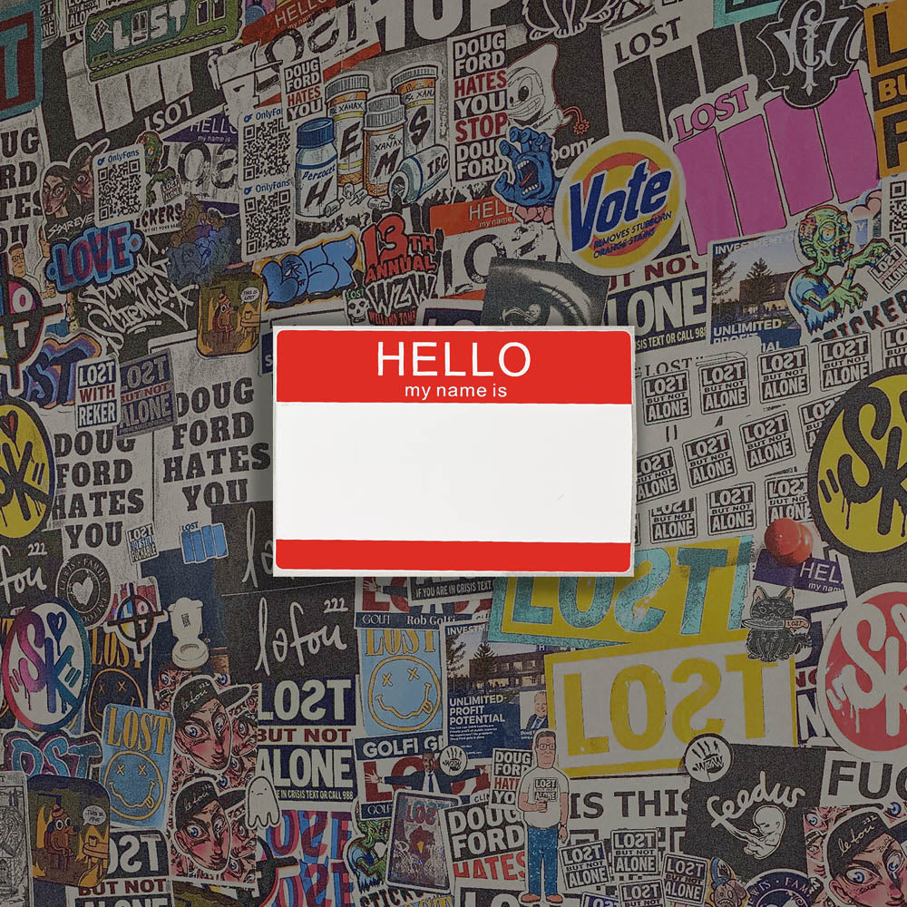 Hello my name is blank nametag sticker. A red and white nametag sticker waiting to be tagged. The sticker is set against a wall of colorful graffiti stickers.