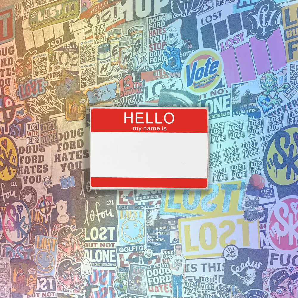 Hello my name is blank nametag sticker. A red and white nametag sticker waiting to be tagged. The sticker is set against a wall of colorful graffiti stickers.