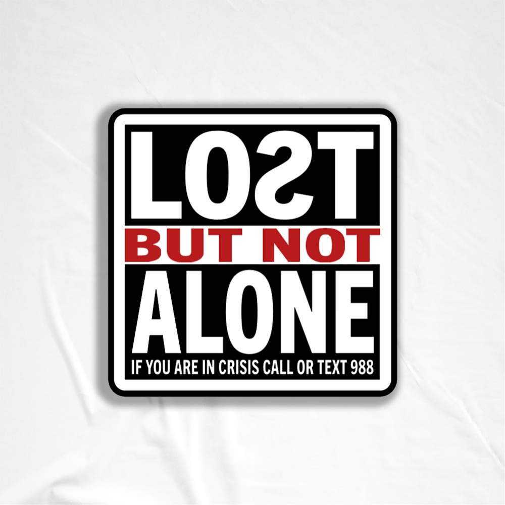 The Lost But Not Alone Sticker by artist and mental health advocate Christopher Reilly. This squared sticker features text stating Lost But Not Alone, if you are in crisis call or text 988. The black, white and red sticker design promotes mental health awareness and suicide prevention.