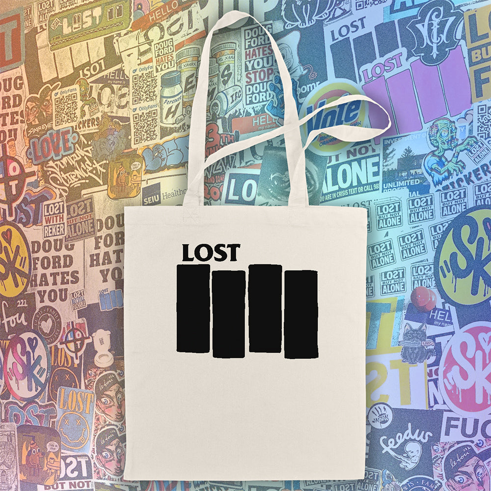 The Lost Flag tote bag. Four Solid black bars  and the word LOST printed across a large, natural canvas tote bag. An assortment of colorful graffiti stickers makes up the display background.  