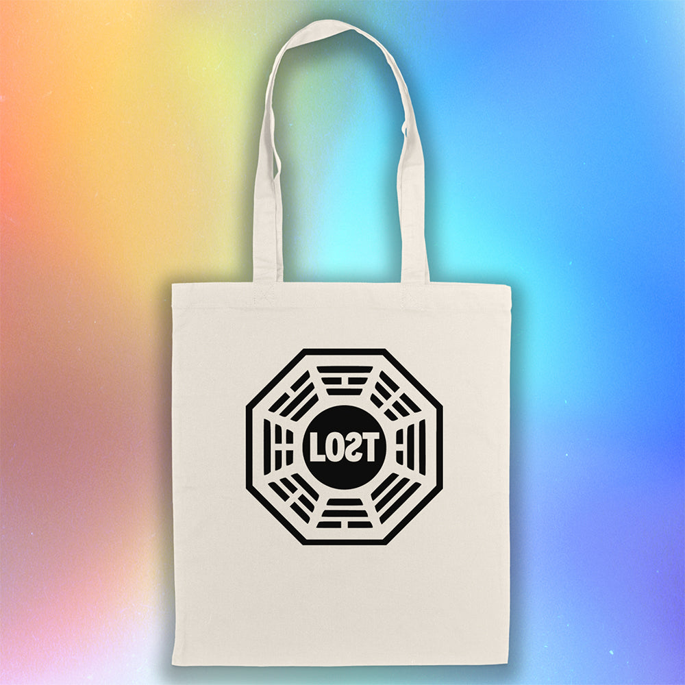 The bold and iconic octagon logo with the word LOST printed in bold black ink and displayed on a large natural canvas tote bag. A holographic rainbow background gives depth to the tote bag on display.  