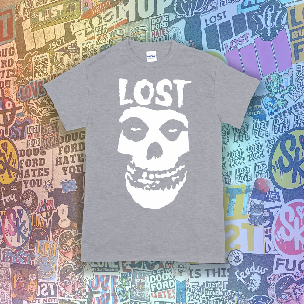The Lost Crimson Ghost t-shirt. A Bold white skull screen printed and displayed on a grey shirt. An assortment of graffiti stickers sets the background for this classic design upgraded by Lost Streetwear.