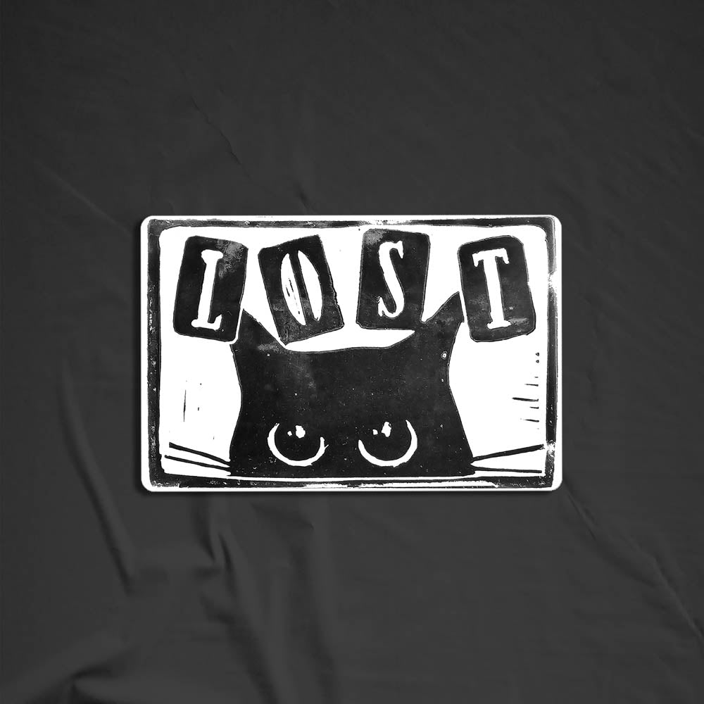 Peekers the cat graffiti sticker by LOST. A black and white image of a black cat peeking out at you with LOST written in above it. The sticker is set against a black background.