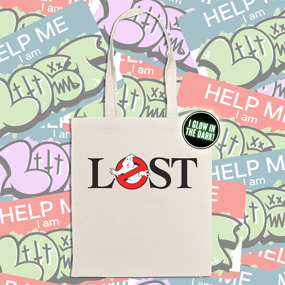 The LOSTBUSTERS tote bag features a surprised looking  ghost trapped in the O of the word LOST and vaguely resembling the original Ghostbusters logo. The crisp image is screen printed on a natural canvas tote bag. A wall of colorful graffiti stickers creates a vibrant background for the tote bag on display.