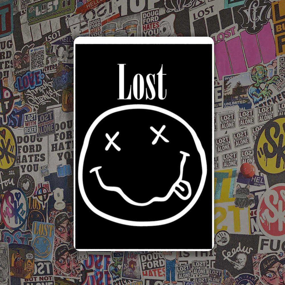 The In Bloom sticker by LOST. Black and white smiley face design with  LOST written above it. A wall of colorful graffiti stickers provides a unique background for the sticker.