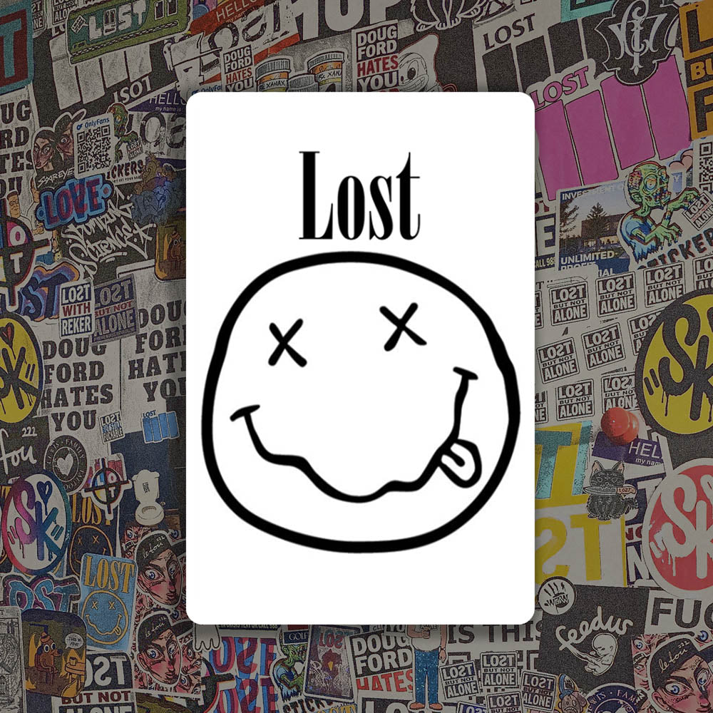 The In Bloom sticker by LOST. Black and white smiley face design with  LOST written above it. A wall of colorful graffiti stickers provides a unique background for the sticker.