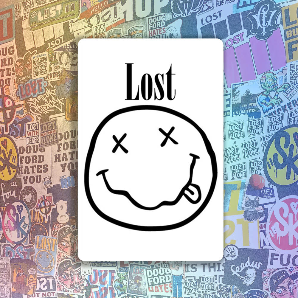 The In Bloom sticker by LOST. Black and white smiley face design with  LOST written above it. A wall of colorful graffiti stickers provides a unique background for the sticker.