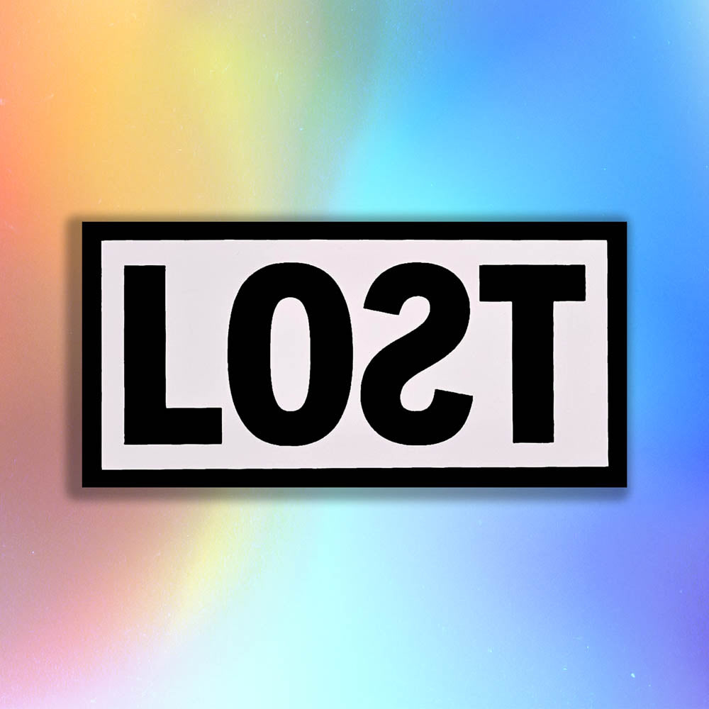 The original graffiti sticker by LOST. A simple two color cut design featuring the word LOST written with a backwards S in black and contained within a matte white rectangle. The sticker is set against a rainbow holographic background.