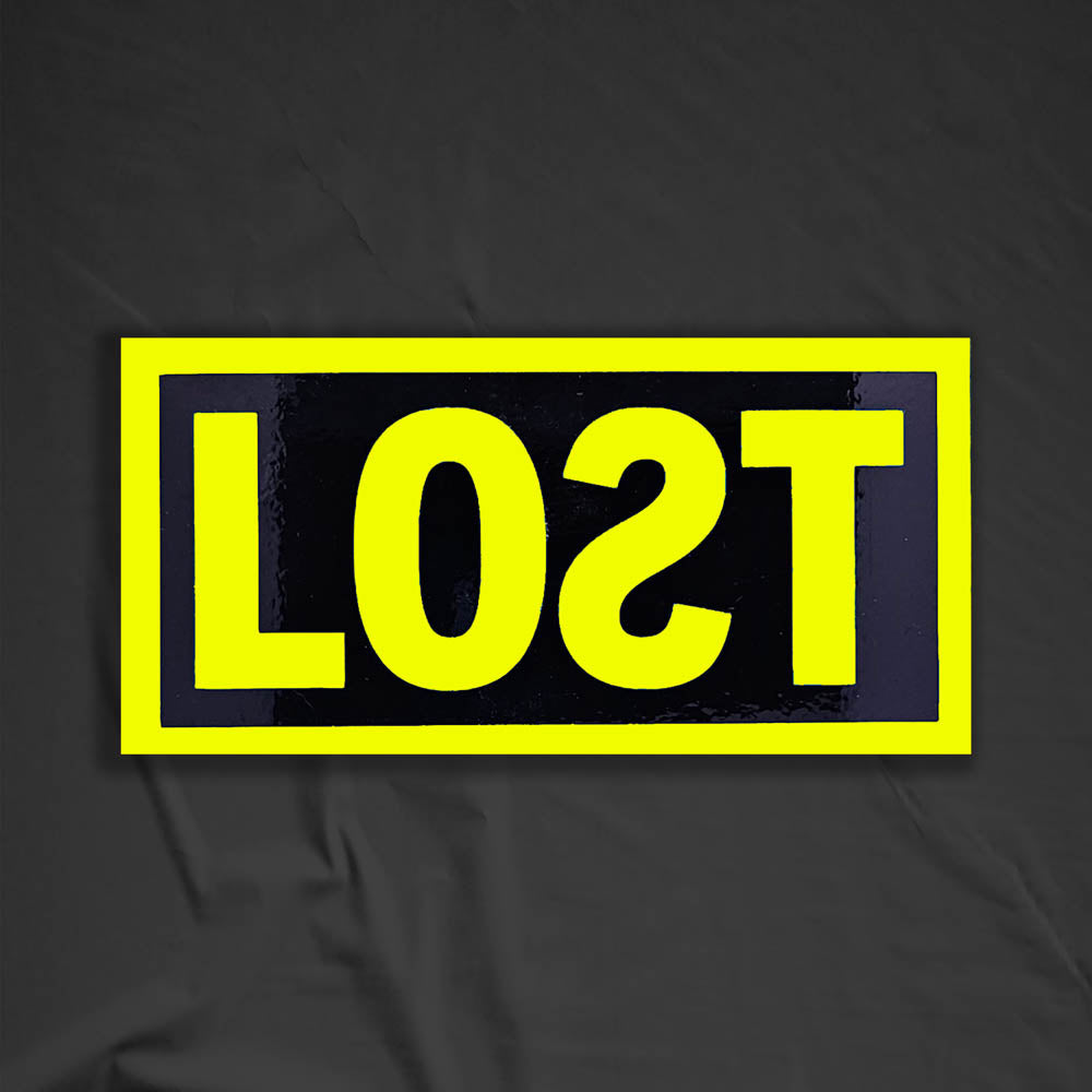 The original graffiti sticker by LOST. A simple two color cut design featuring the word LOST written with a backwards S in bright yellow and contained within a glossy black rectangle. The sticker is set against a contrasting black background.