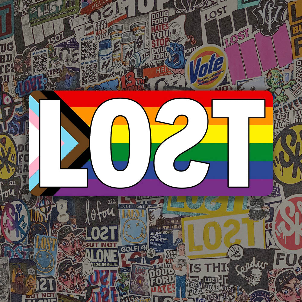 The LOST Progress graffiti sticker. The word LOST written in bold white letters on top of a rainbow progress flag. The sticker is displayed against a background of colorful graffiti stickers.