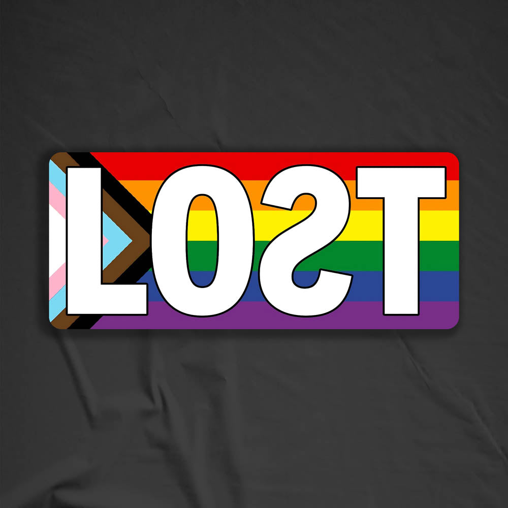 The LOST Progress graffiti sticker. The word LOST written in bold white letters on top of a rainbow progress flag. The sticker is displayed against a black background.