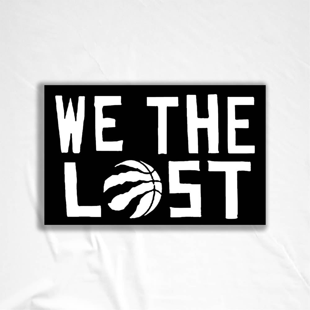 The We The Lost graffiti sticker. Bold white lettering and raptor claw design on a black sticker. The O in the word LOST is a basketball with claws. The sticker is set against a white textured background.