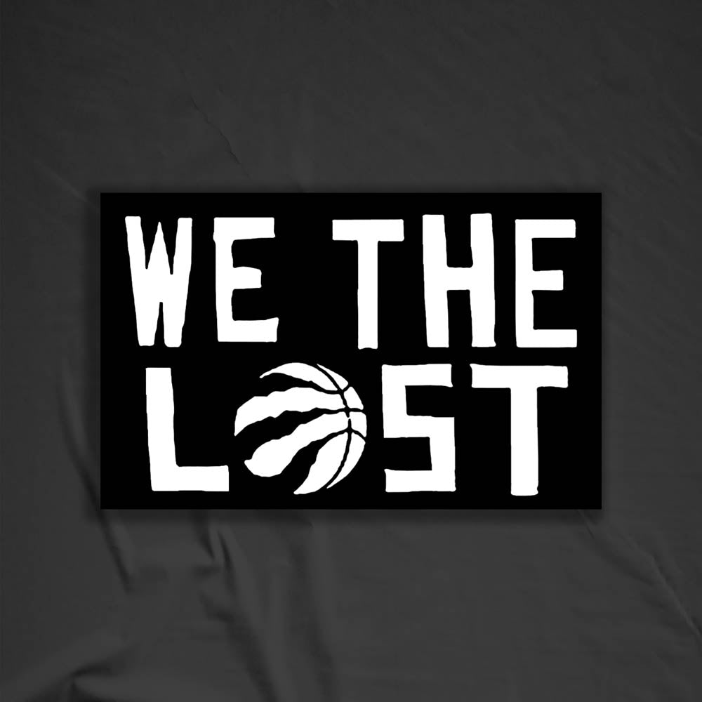 The We The Lost graffiti sticker. Bold white lettering and raptor claw design on a black sticker. The O in the word LOST is a basketball with claws. The sticker is set against a textured black background.