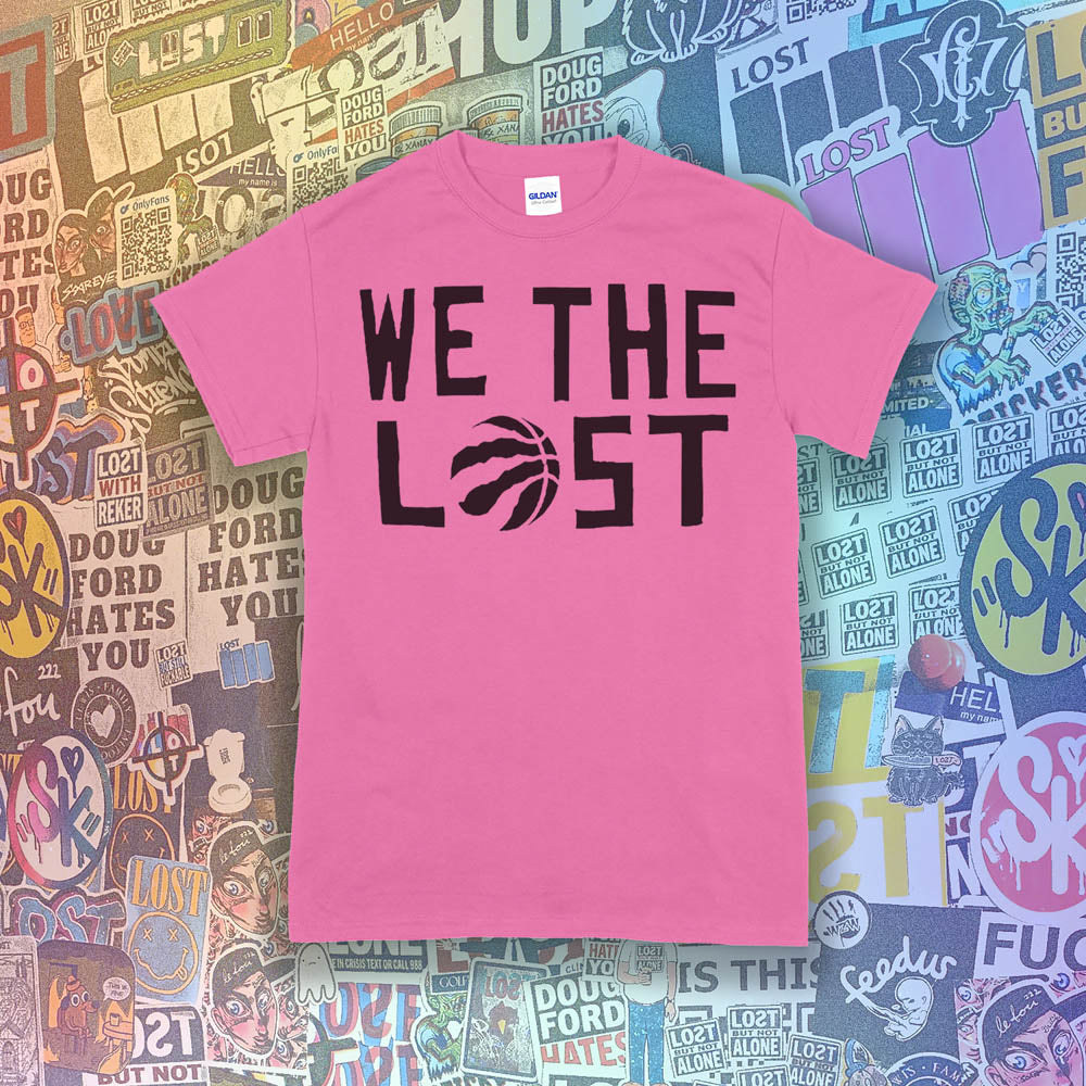 We The Lost t-shirt. Bold black lettering and raptor claw design screen printed on a bright pink shirt. A wall of colorful graffiti stickers make up the background.