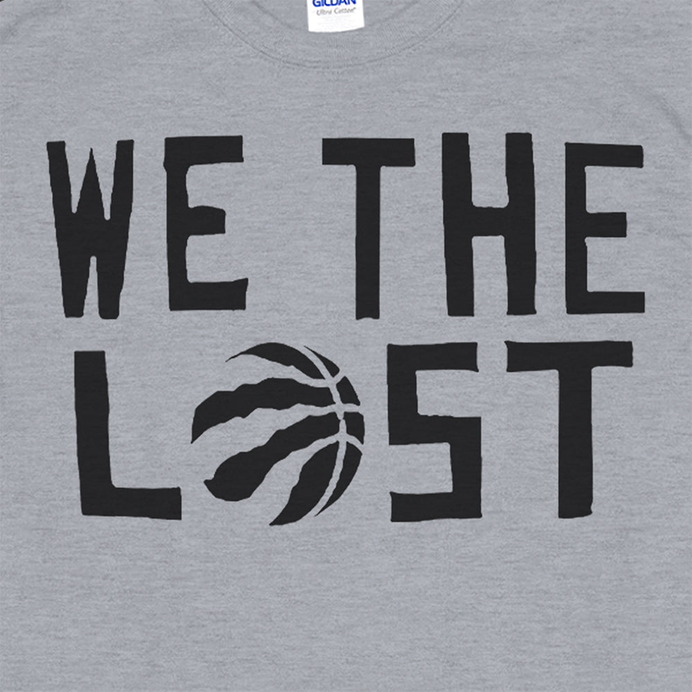 Close up view of the We The Lost t-shirt. Bold black lettering screen printed on a gray shirt.
